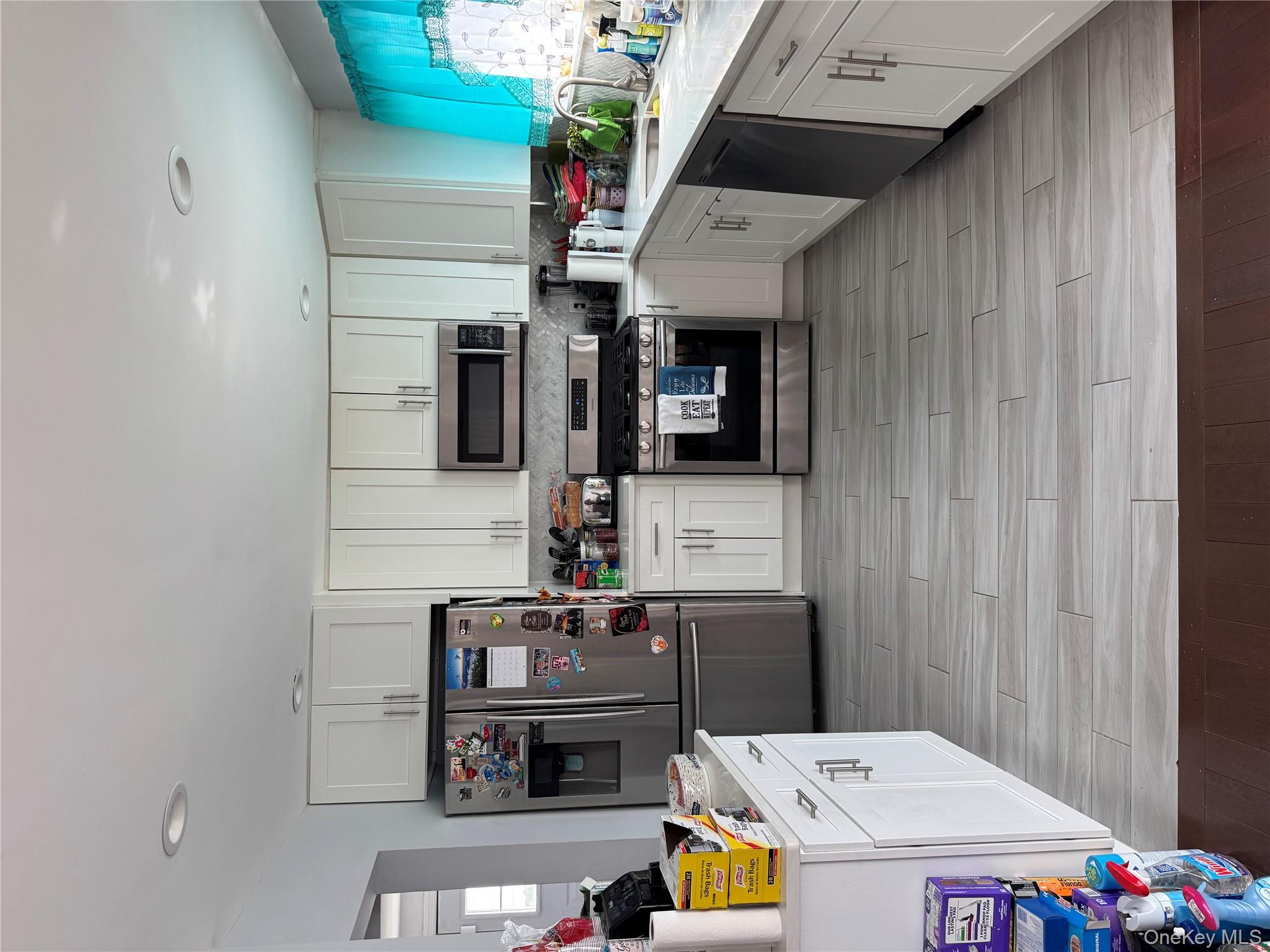 8 Frazier Street Hempstead, NY 11550 - Photo 3 of 7 a kitchen with stainless steel appliances a stove top oven a microwave a refrigerator a sink dishwasher and white cabinets with wooden floor