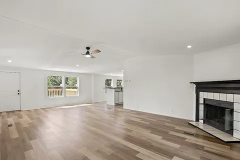 a kitchen with stainless steel appliances granite countertop a refrigerator a sink a stove and white cabinets with wooden floor