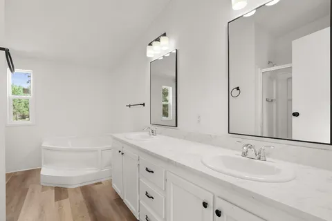 a bathroom with a double vanity sink a mirror and a bathtub