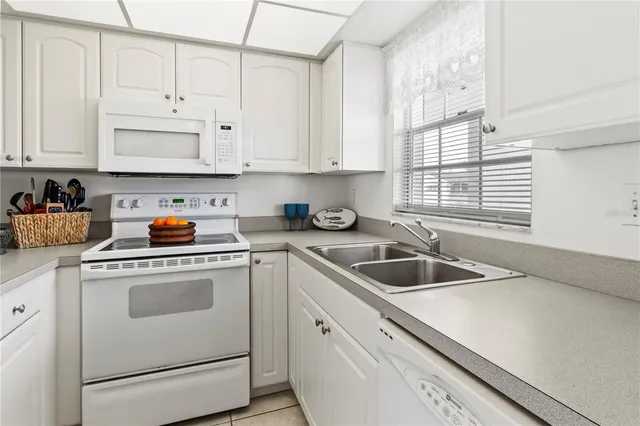 a kitchen with granite countertop white cabinets white appliances and a sink
