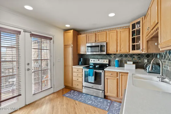 a kitchen with stainless steel appliances granite countertop a stove a sink dishwasher a microwave oven and a refrigerator with wooden floor