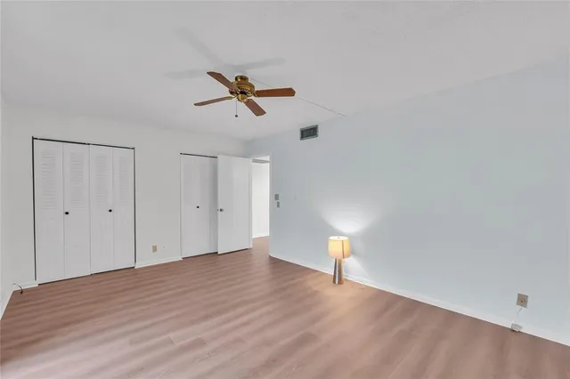 a view of empty room with wooden floor and ceiling fan