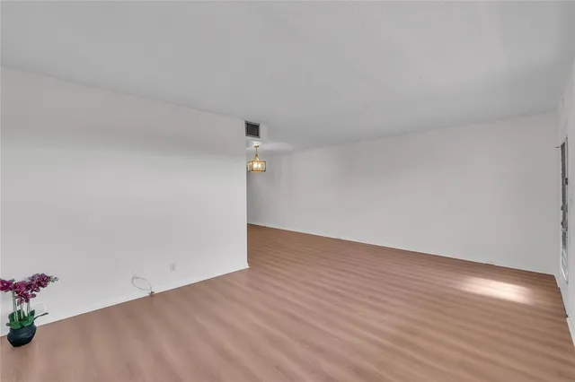 a view of an empty room with wooden floor