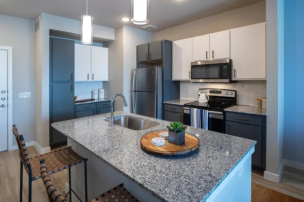 a kitchen with stainless steel appliances granite countertop a sink dishwasher a stove and refrigerator with wooden floor