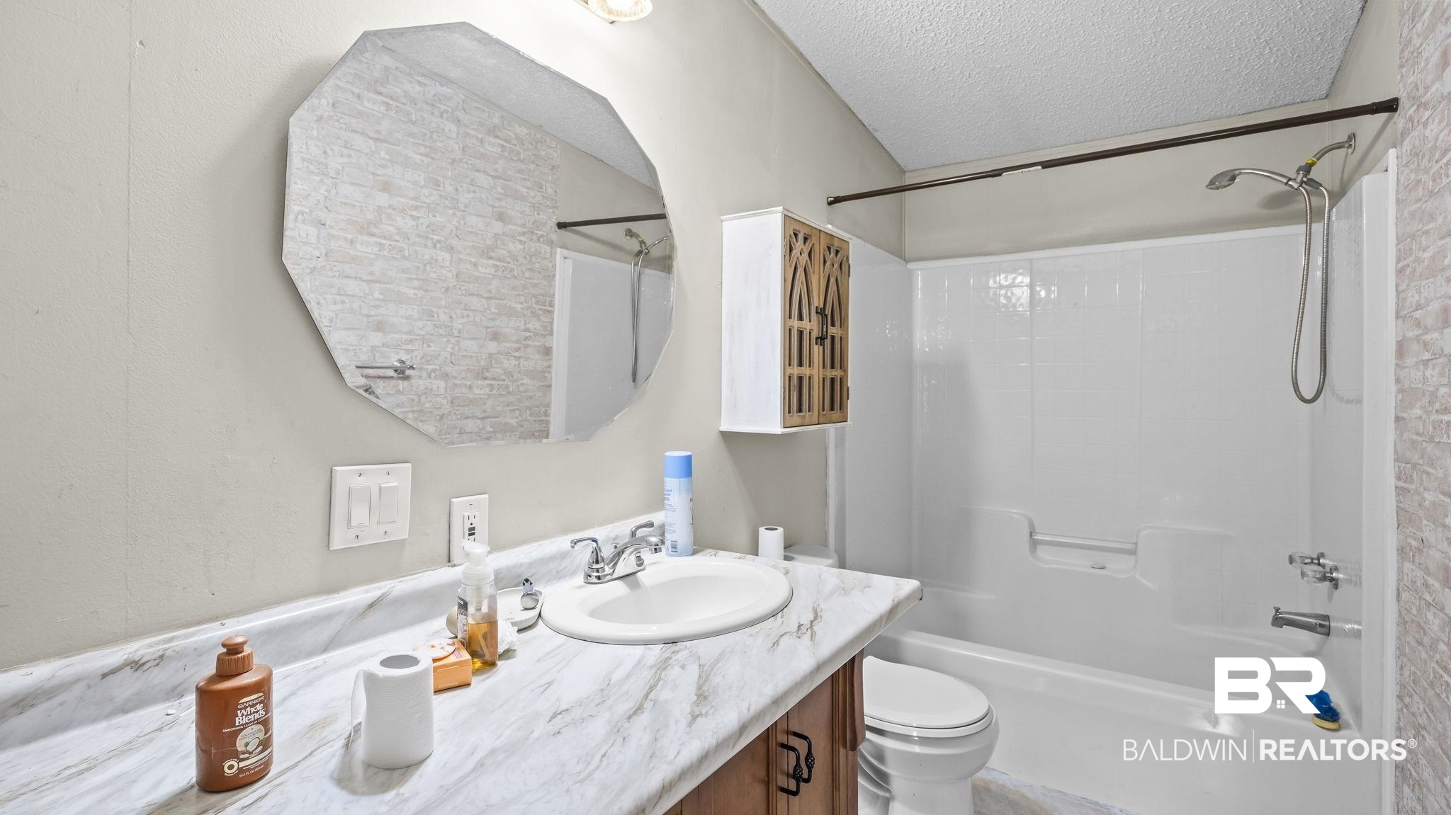 34985b Spring Road South, Unit B Stapleton, AL 36578 - Photo 12 of 31 Bathroom featuring a single vanity with a laminate countertop, an undermount sink, and a framed octagonal mirror