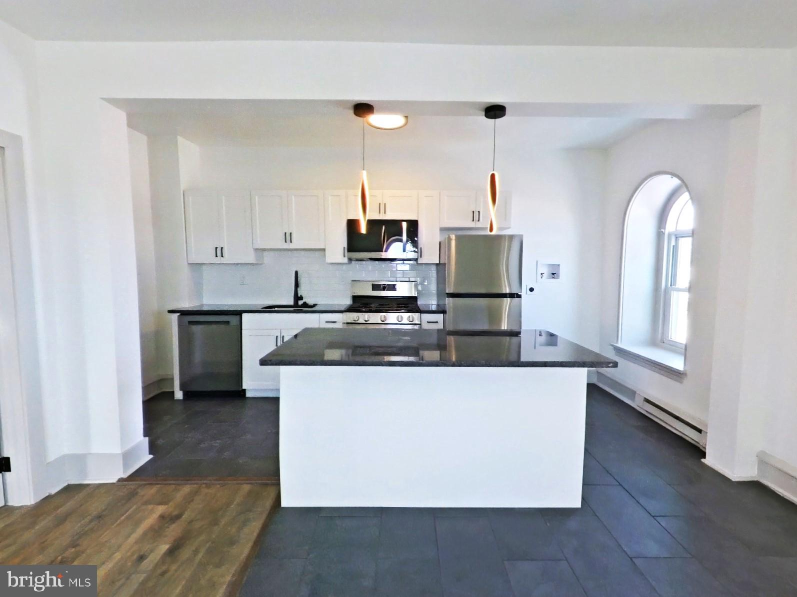 5606 Ridge Avenue, Unit 3F Philadelphia, PA 19128 - Photo 9 of 10 a kitchen with stainless steel appliances granite countertop a stove a sink and a refrigerator
