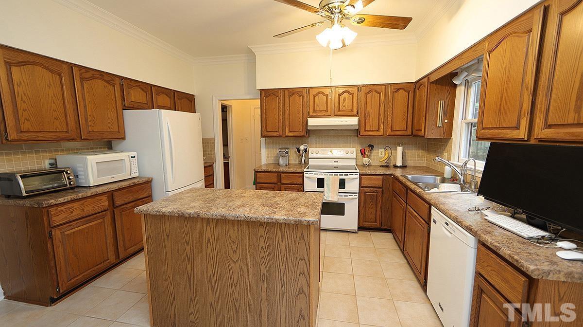 8700 Mourning Dove Road Raleigh, NC 27615 - Photo 10 of 30 a kitchen with stainless steel appliances granite countertop a stove top oven a refrigerator a sink and dishwasher with wooden floor