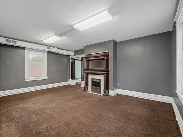 an empty room with windows and fireplace