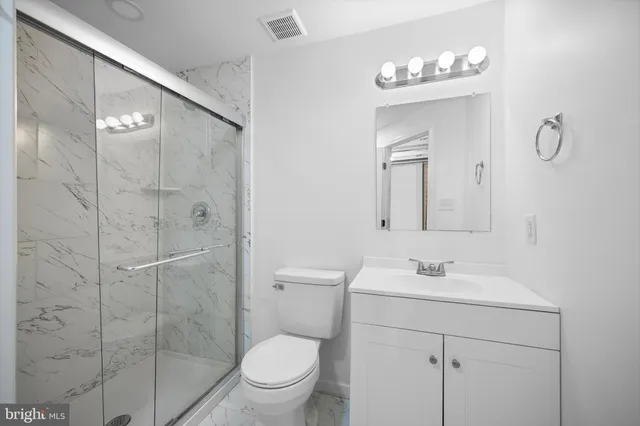 a bathroom with a toilet sink vanity granite and shower