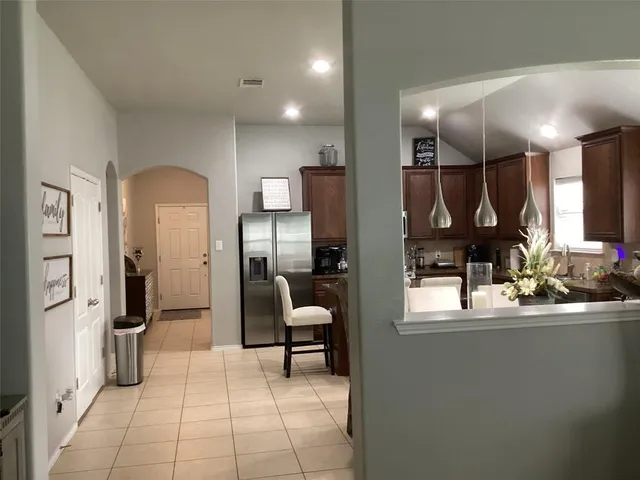 a kitchen with stainless steel appliances kitchen island granite countertop a refrigerator and a sink