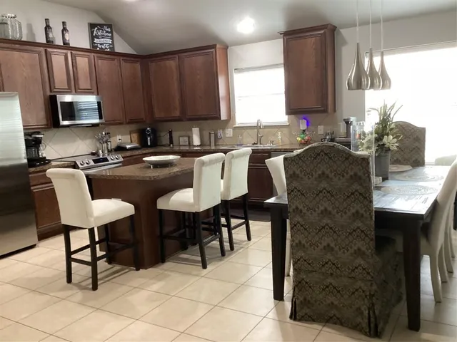 a kitchen with stainless steel appliances granite countertop a table chairs microwave and sink