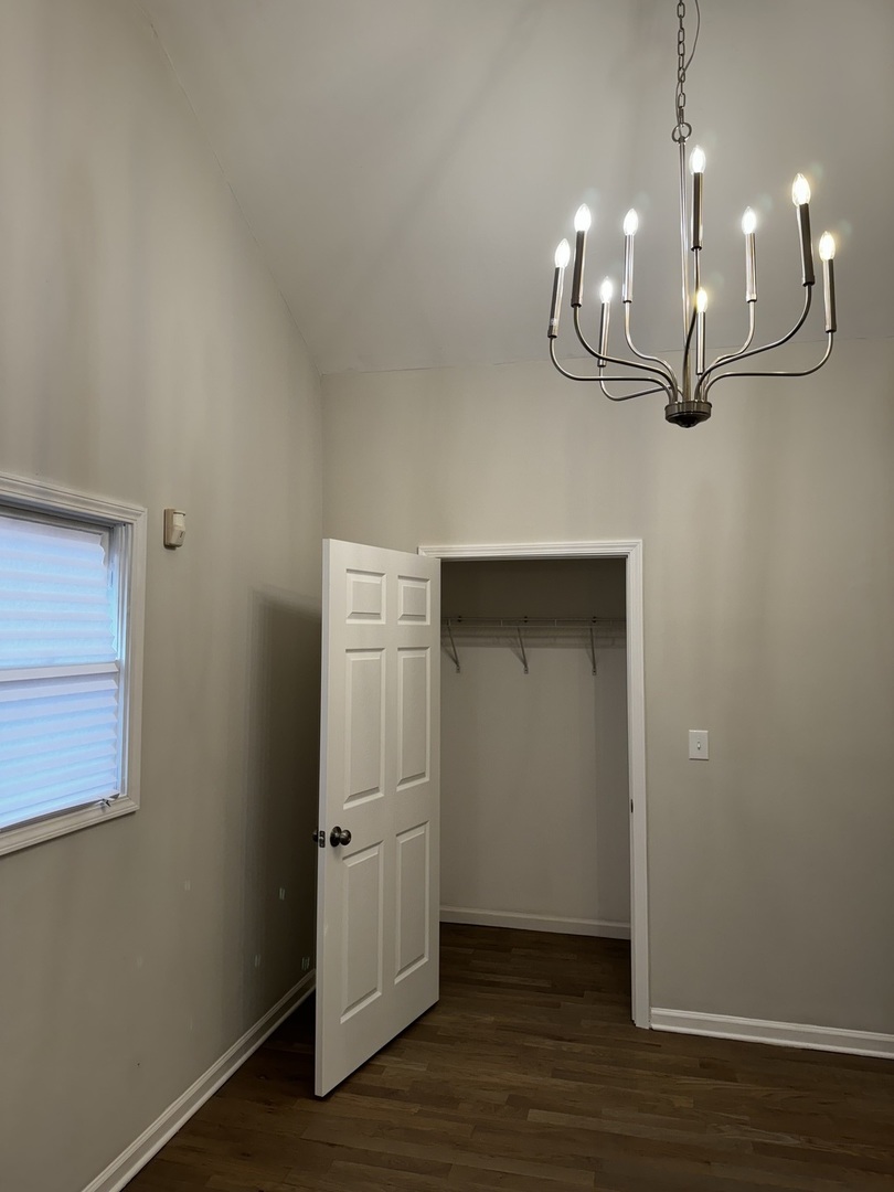 5525 South Emerald Avenue Chicago, IL 60621 - Photo 13 of 29 an empty room with wooden floor and kitchen view