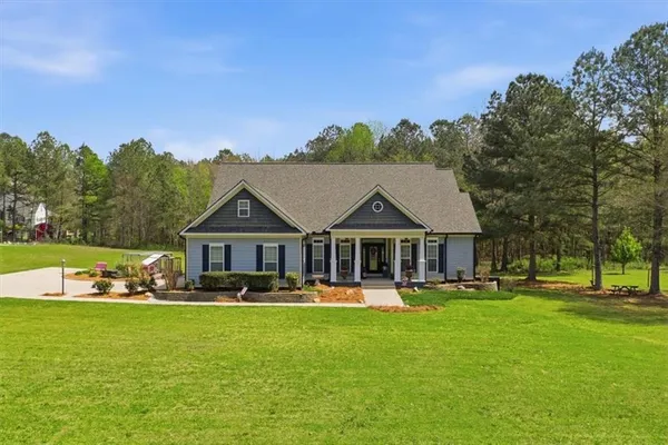 a front view of a house with garden and trees
