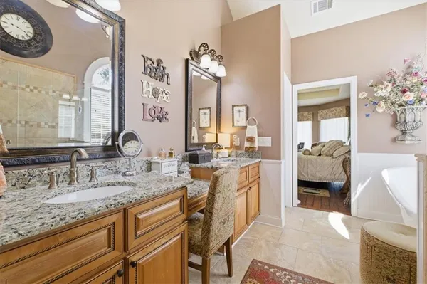 a en suite bathroom with a granite countertop sink a large mirror and a shower