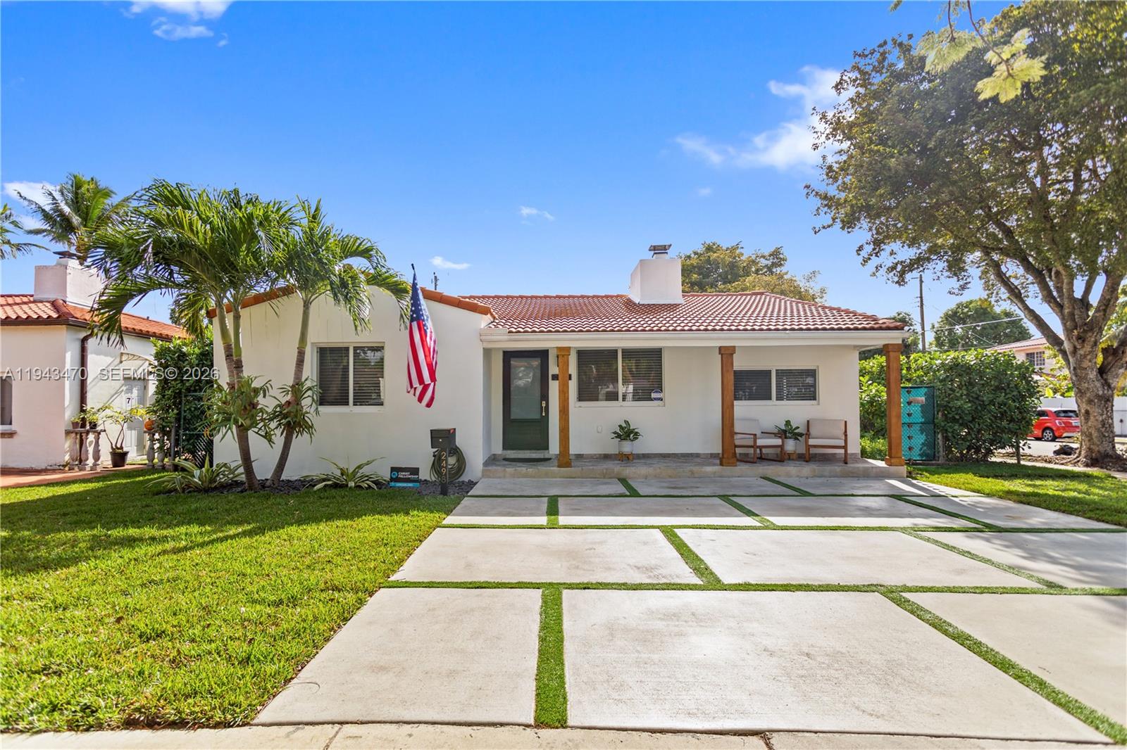 a view of a white house with a swimming pool and a lawn chairs under a large tree