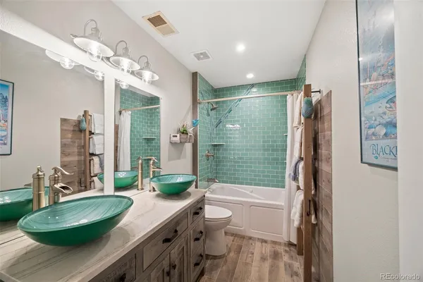 a bathroom with a granite countertop sink a toilet a mirror and shower