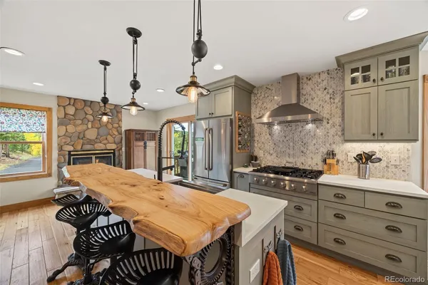 a kitchen with stainless steel appliances a stove a sink a dining table and chairs with wooden floor
