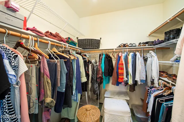 a view of walk in closet with clothes and shoes