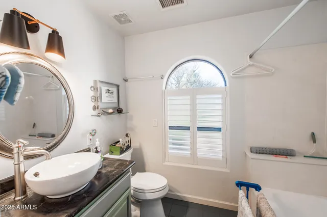 a bathroom with a granite countertop toilet a sink and a mirror