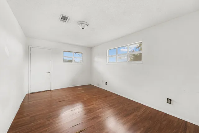 an empty room with wooden floor and windows