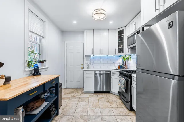 a kitchen with stainless steel appliances granite countertop a stove top oven a sink dishwasher and a refrigerator with wooden cabinets