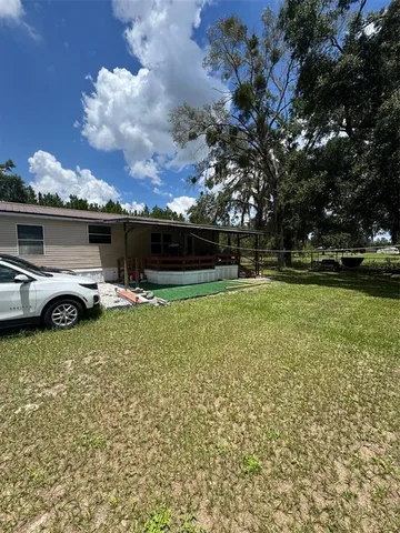 a view of a house with a big yard and a large tree