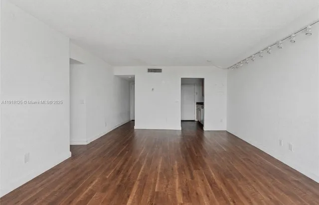 a view of an empty room with wooden floor and cabinets