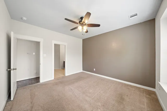 an empty room with closet and a ceiling fan