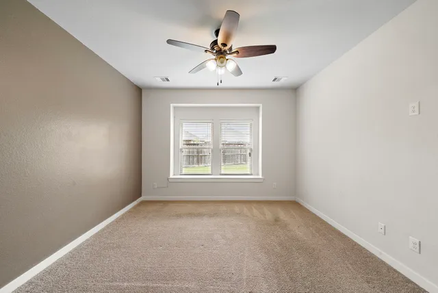 an empty room with a window and a fan