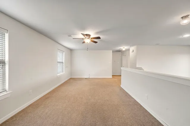 an empty room with windows and chandelier fan