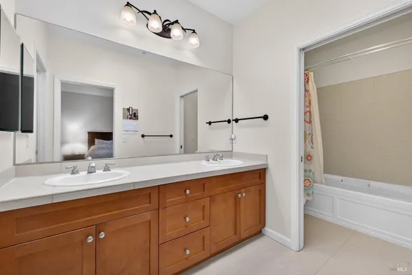 a spacious bathroom with a double vanity sink a large mirror and shower