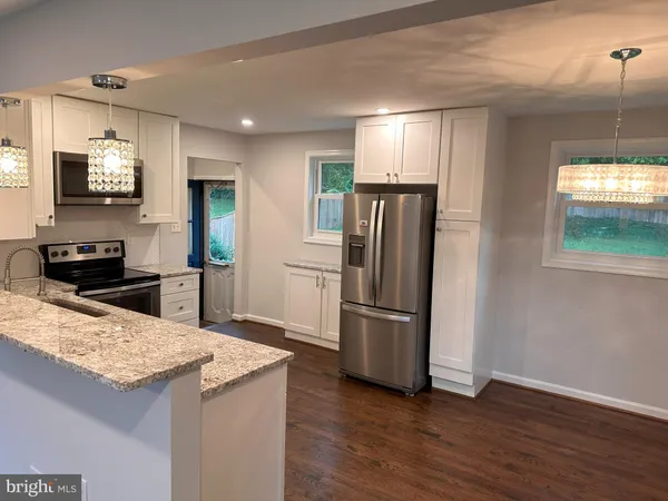 a kitchen with granite countertop a refrigerator and a stove top oven
