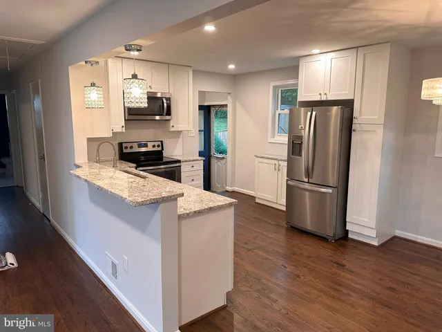 a kitchen with a refrigerator a stove top oven and wooden floor