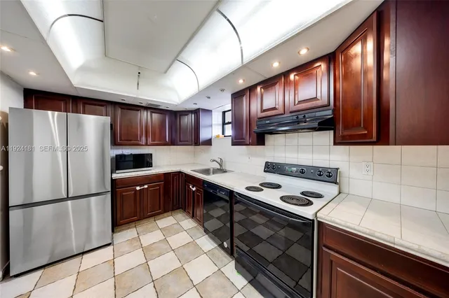 a kitchen with a sink stainless steel appliances a refrigerator and cabinets