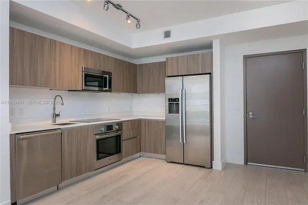 a kitchen with stainless steel appliances granite countertop a refrigerator a sink a stove a microwave and island