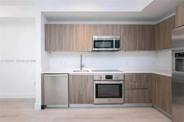 a kitchen with stainless steel appliances a stove microwave and sink