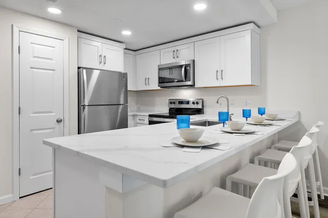 a kitchen with stainless steel appliances granite countertop a refrigerator a stove a sink a microwave and white cabinets