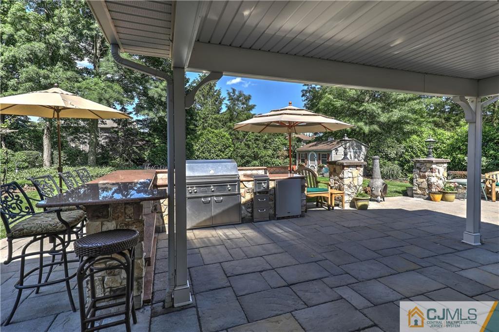 23 Winterberry Circle Piscataway, NJ 08854 - Photo 4 of 29 a patio with a table and chairs under an umbrella with a small yard