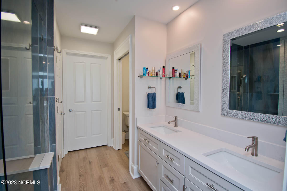 1435 Salter Path Road, Unit I 2 Indian Beach, NC 28512 - Photo 12 of 54 During the 2023 bathroom renovation, the original garden tub was removed, allowing room for an additional closet. Luxury, vinyl-planked flooring, a new quartz countertop, new sinks, and new bathroom fixtures and mirrors round out this beautiful space.