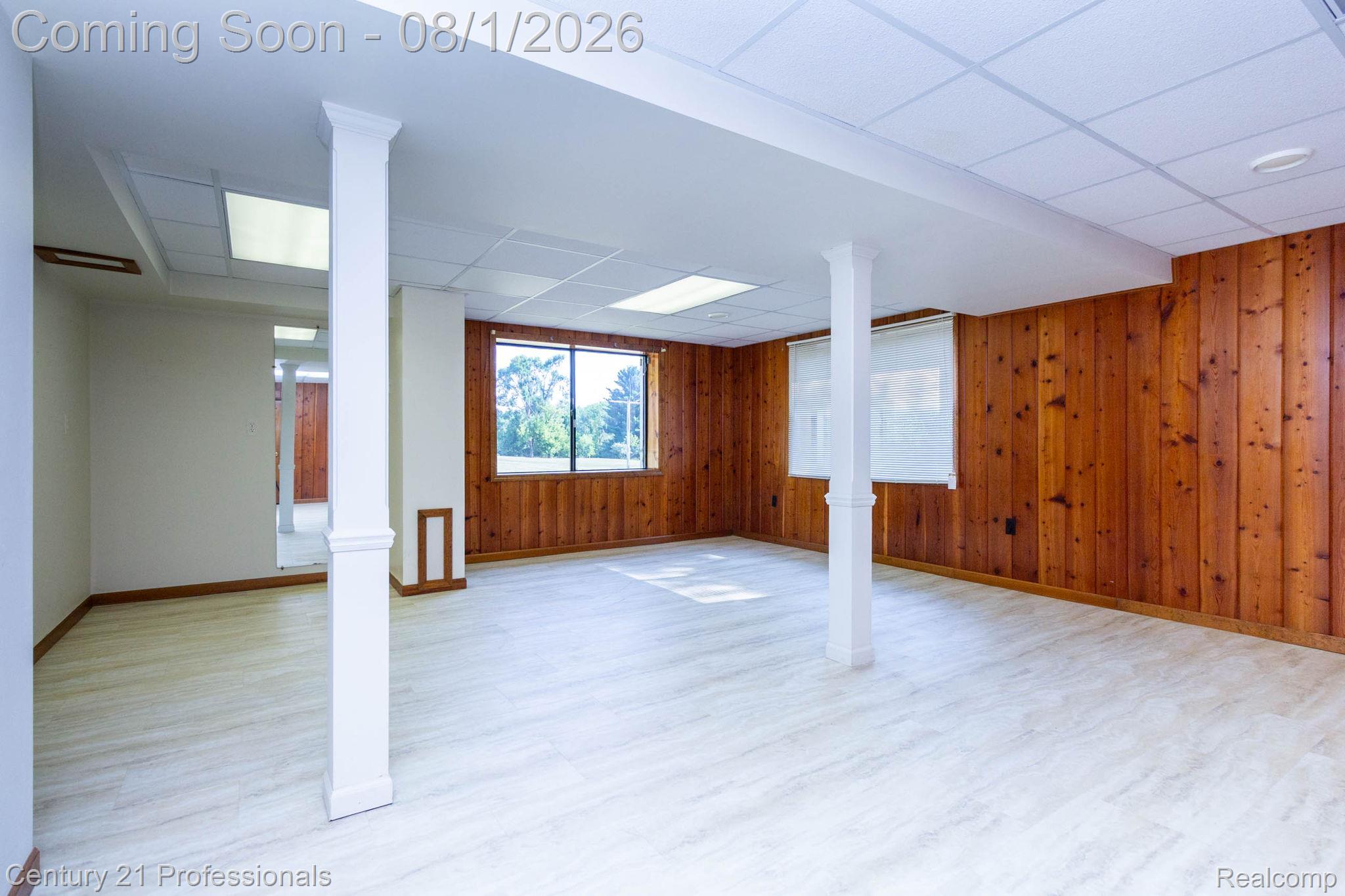 1365 East Buell Road Rochester, MI 48306 - Photo 26 of 56 Spacious room featuring wood paneling, light-toned wood-finish flooring, and white support columns