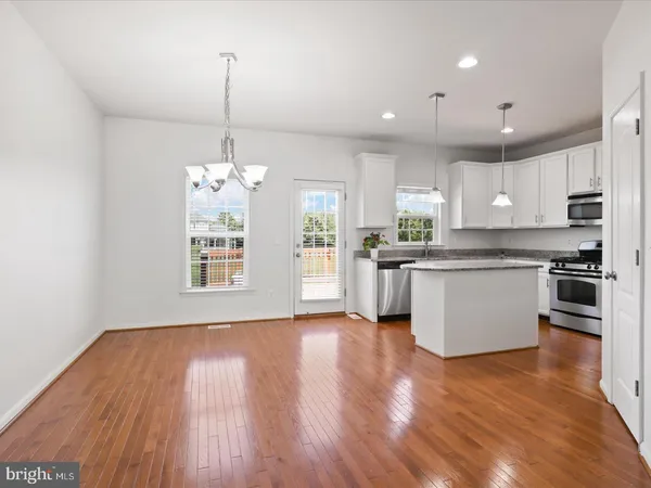 a kitchen with stainless steel appliances granite countertop wooden floors and white cabinets