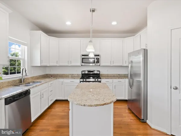 a kitchen with kitchen island a counter top space cabinets and stainless steel appliances