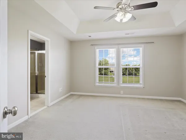 an empty room with chandelier fan and windows