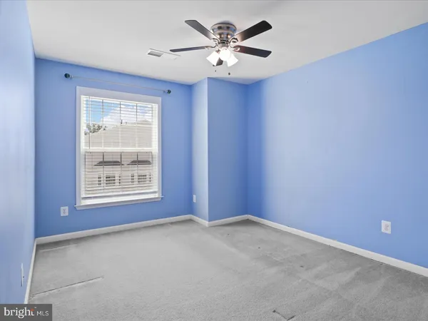 an empty room with a window and a fan