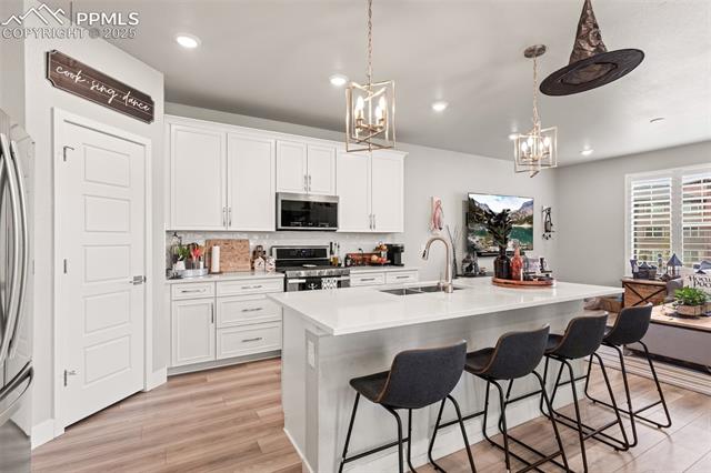 8258 Mount Ouray Road Littleton, CO 80125 - Photo 7 of 28 Kitchen featuring appliances with stainless steel finishes, sink, pendant lighting, and a kitchen island with sink
