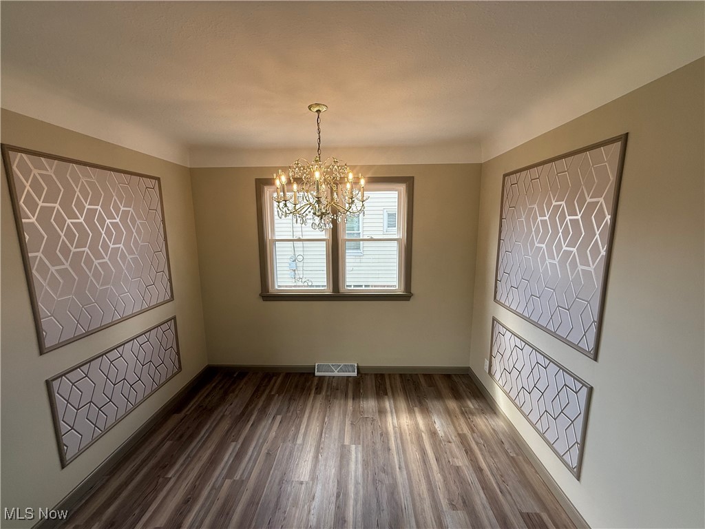 9417 Alexander Road Garfield Heights, OH 44125 - Photo 16 of 38 Unfurnished dining area with an inviting chandelier, baseboards, dark wood finished floors, and visible vents