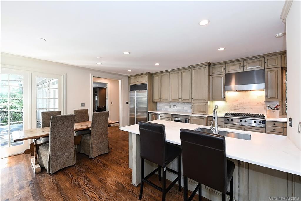 1626 Queens Road West Charlotte, NC 28207 - Photo 2 of 36 a kitchen with stainless steel appliances granite countertop wooden floor cabinets dining table and chairs