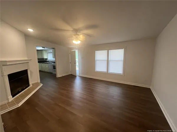 an empty room with wooden floor fireplace and windows