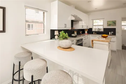a kitchen with stainless steel appliances a white table chairs and a refrigerator