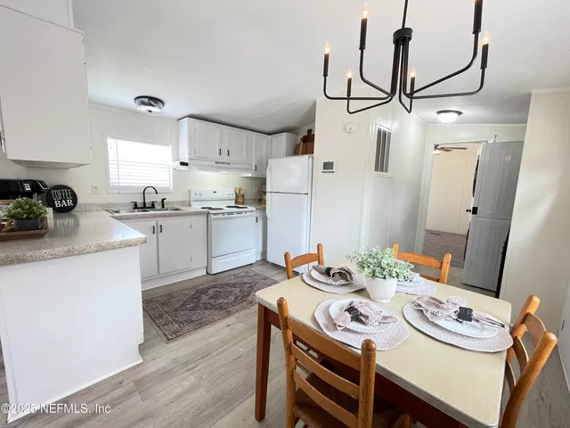 a kitchen with stainless steel appliances granite countertop a sink a stove a chimney a dining table and chairs